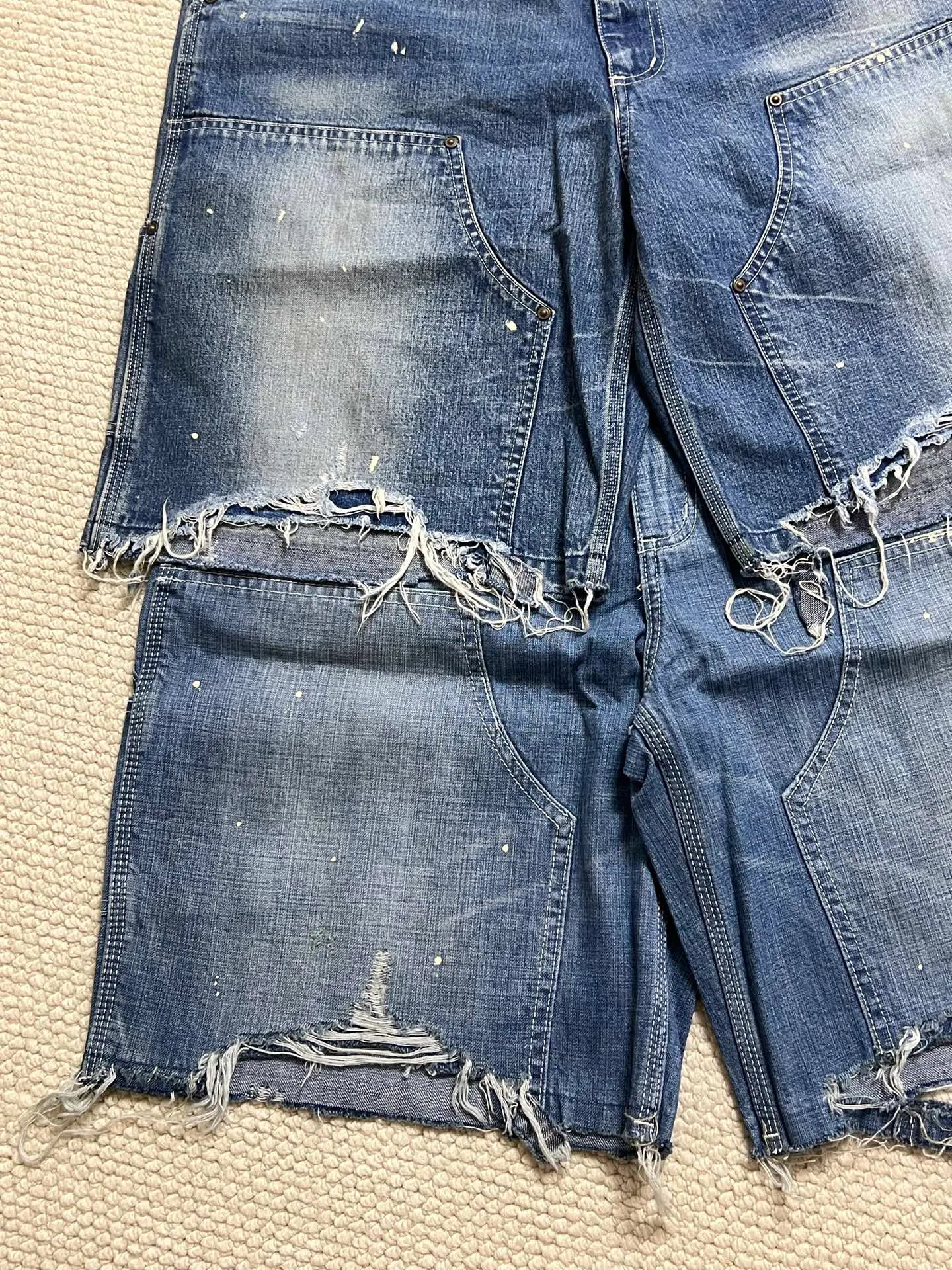 SAINT Mxxxxxx DOUBLE KNEE SHORTS/BLU Knee patches splashed with ink and water-splashed denim shorts. Denim blue S-XL. Custom-woven and dyed denim fabric with clear texture. Heavy-wash water-fading treatment to create local mottled fading/hole effects. Artificial distressing to simulate natural wearing marks. VINTAGE sense. Original consistent damage treatment. Hand-splashed ink and paint. Original consistent wash mark/pocket mark. Double knee patch. Rivet reinforcement. Improve functionality while enhancing design